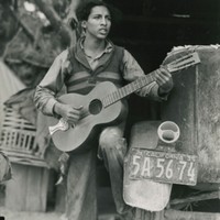 A young Mexican farm worker plays guitar and sings in a Coachella Valley labor camp